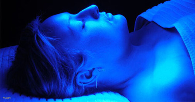 woman lying on a table under blue light