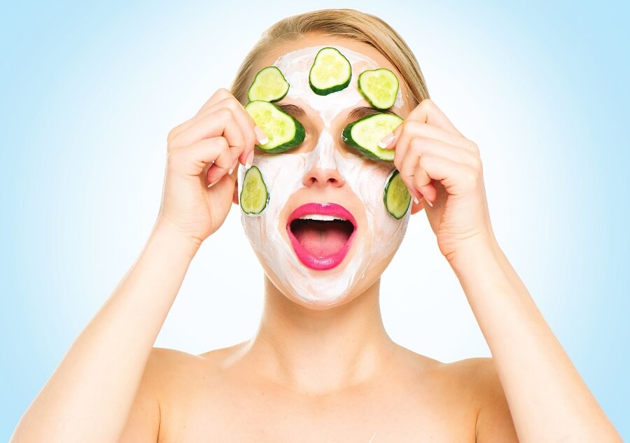 woman applying cucumber slices to her yogurt mask