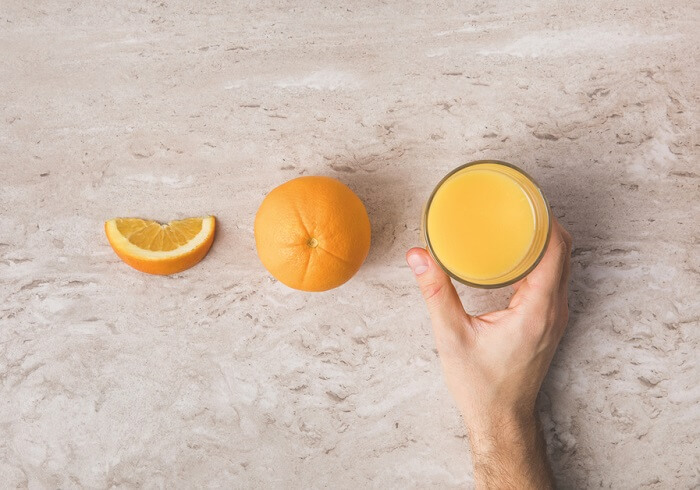 Cropped image of man taking glass of fresh orange juice from table